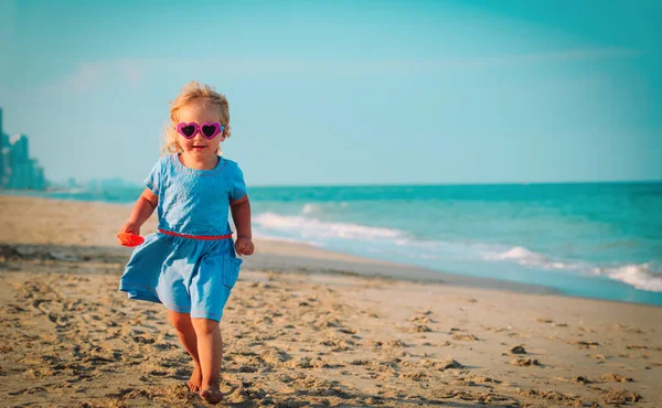 Счастливая милая маленькая девочка бежит играть на пляже — стоковое фото