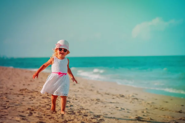 Счастливая милая маленькая девочка бежит играть на пляже — стоковое фото