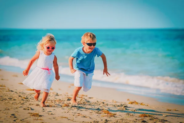 Kisfiú és a lány fut játszani beach — Stock Fotó