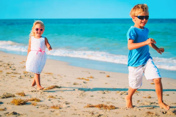 Malý chlapec a dívka spustit hrát na pláži — Stock fotografie