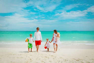 Üç çocuklu mutlu bir aile sahilde yürüyor.