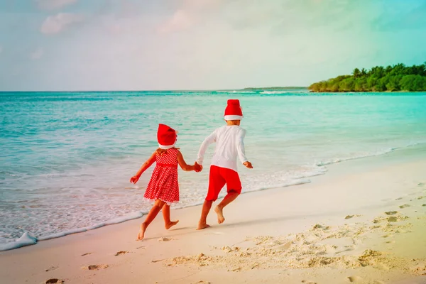 Navidad en la playa niño y niña en divertirse en el mar —  Fotos de Stock