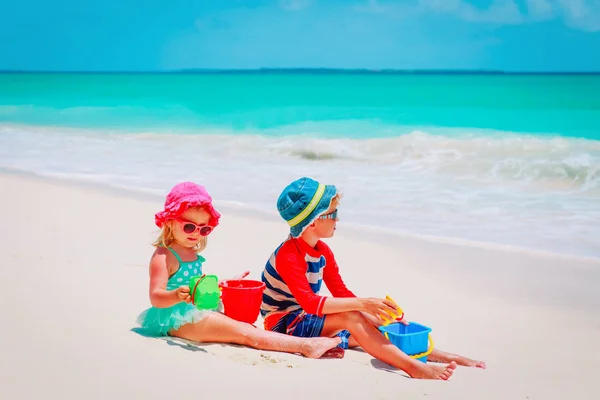 Menino e menina brincam com areia na praia — Fotografia de Stock