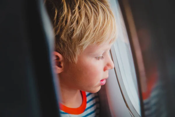 Niño viajando en avión mirando por la ventana — Foto de Stock