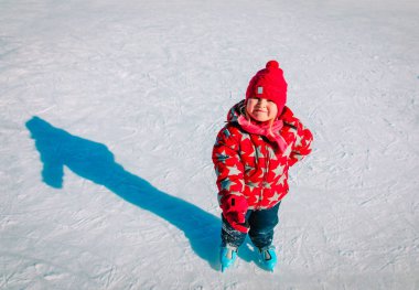 Mutlu küçük kız kışın paten kaymayı öğreniyor.