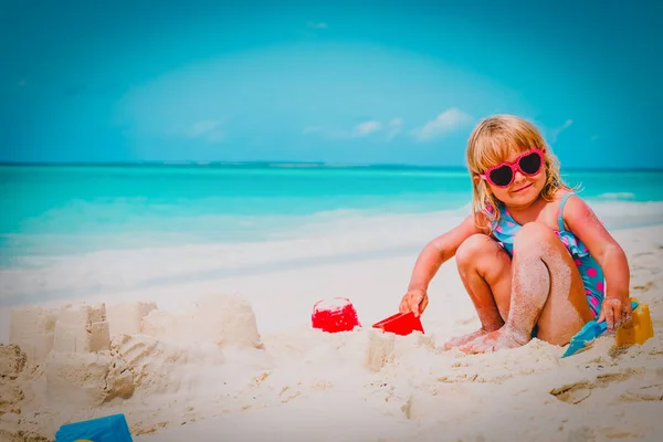 Niedliche kleine Mädchen spielen mit Sand am Strand — Stockfoto