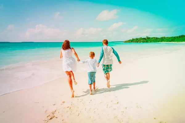 Família feliz com criança desfrutar de praia tropical — Fotografia de Stock