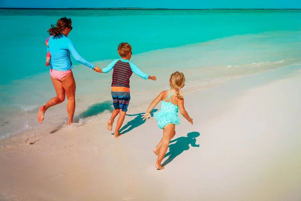 Matka s dětmi hrát s vody na pláži — Stock fotografie