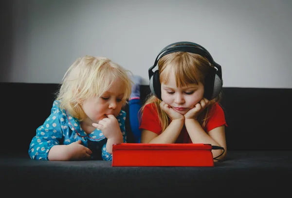 Little girls with headset looking at touch pad — Stock Photo, Image
