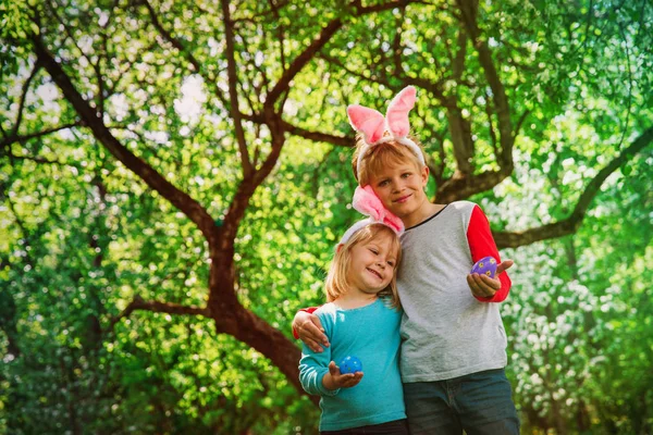 Niños felices - niño y niña - en la caza de huevos de Pascua en primavera — Foto de Stock