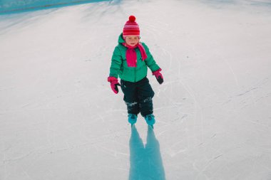 Mutlu küçük kız kışın paten kaymayı öğreniyor.