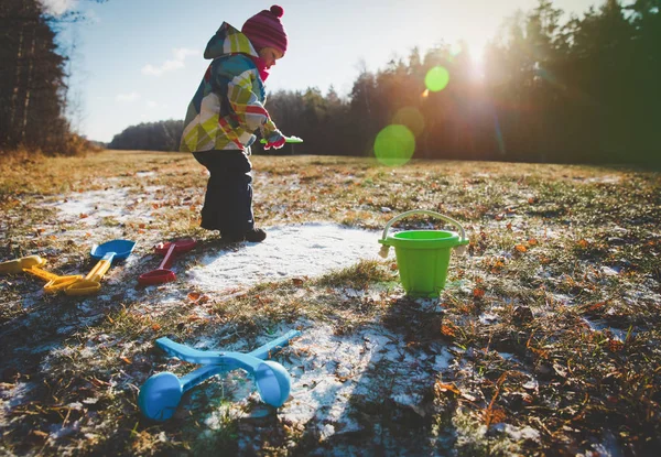 Маленькая девочка играет с первым снегом в природе — стоковое фото