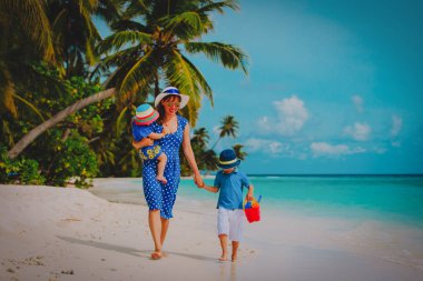 Anne ve oğlu ve kızı sahilde yürüyor.