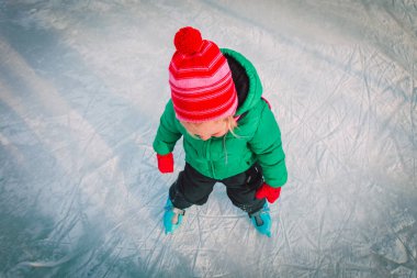 Mutlu küçük kız kışın paten kaymayı öğreniyor.