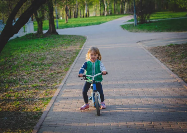 Милая маленькая девочка езда на беговом велосипеде в парке, активные дети — стоковое фото