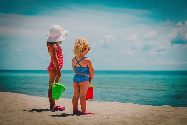 Les petites filles jouent avec le sable sur la plage d'été — Photo