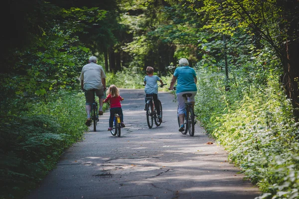 active senior grandparents with kids riding bikes in nature