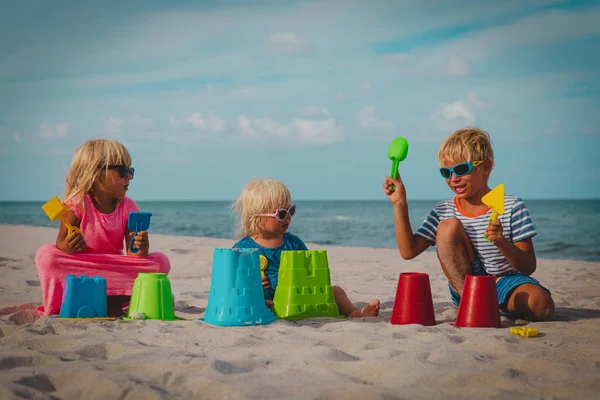 Mutlu çocuklar oyuncaklarla oynamak ve kum plaj tatil — Stok fotoğraf