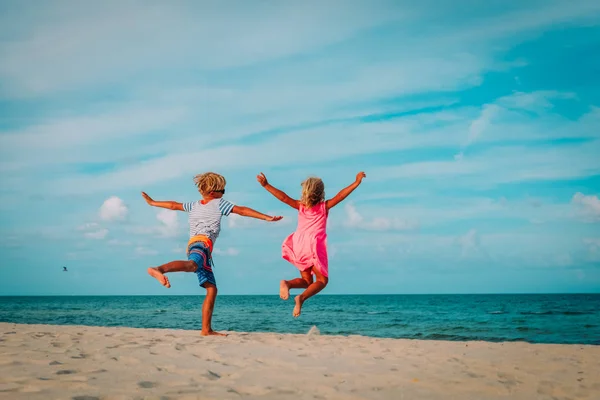 Glad liten pojke och en flicka Njut spela hoppa på stranden — Stockfoto