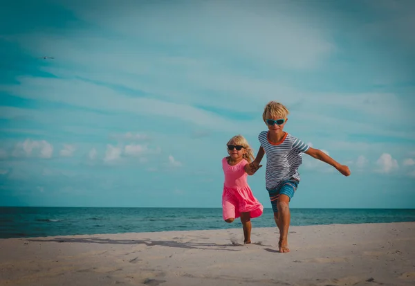 Kleine Jungen und Mädchen rennen am Strand — Stockfoto