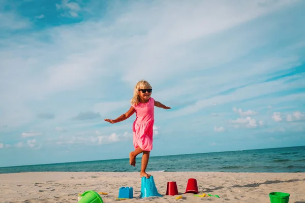 Счастливая маленькая девочка играет с игрушками на пляже — стоковое фото