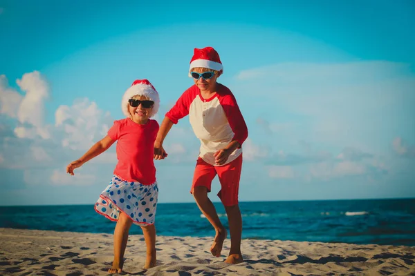 Crianças felizes menino e menina celebrando o Natal na praia — Fotografia de Stock