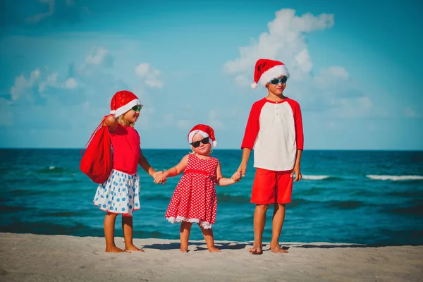 Happy kids- little boy and girls- celebrating christmas on beach — Stock Photo, Image