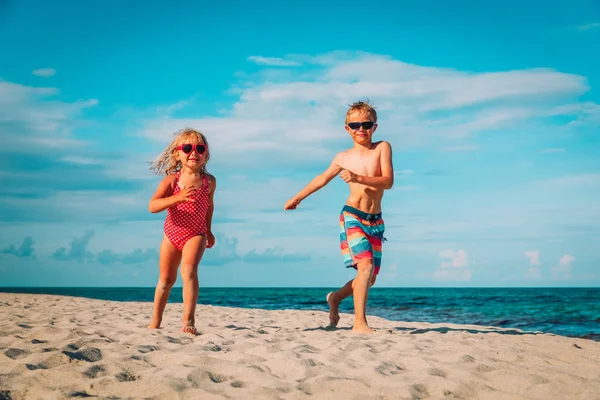 Šťastný malý chlapec a dívka spustit hrát na pláži — Stock fotografie