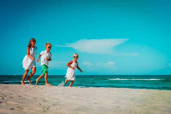 Moeder met kinderen spelen looppas op tropisch strand — Stockfoto