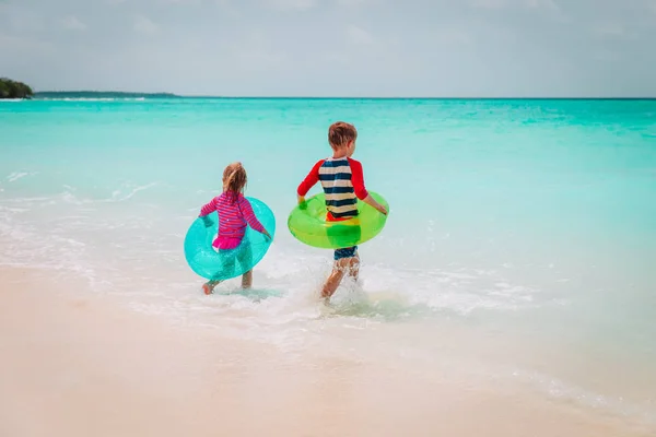 Malou holčičku a chlapce jít plavat na tropické pláži — Stock fotografie