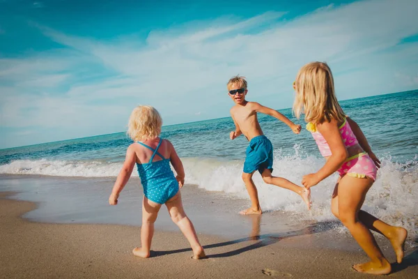 Happy kids - kleine jongen en meisjes-run spelen op het strand — Stockfoto
