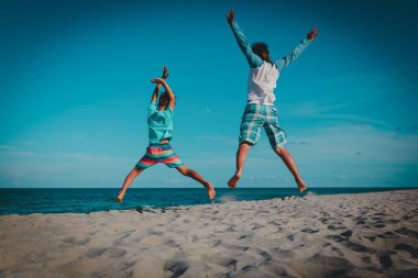 Baba ve oğul tropikal kumsalda atlamak eğlenin