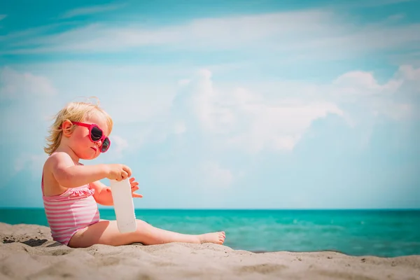 Mignonne petite fille avec crème solaire sur la plage tropicale — Photo