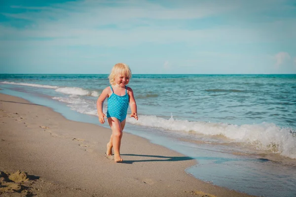 Счастливая маленькая девочка бежит играть наслаждаться песчаным пляжем — стоковое фото