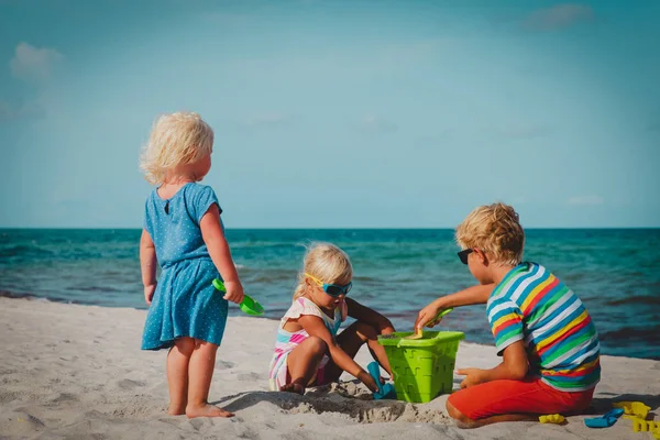 Niños juegan con arena en la playa de verano — Foto de Stock