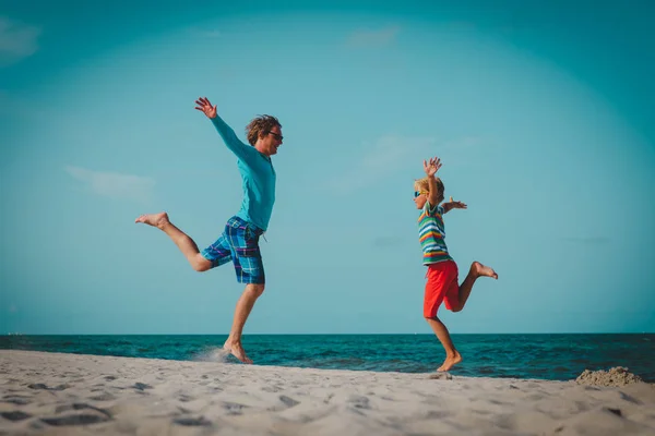 Otec a syn bavit skákat na tropické pláži — Stock fotografie