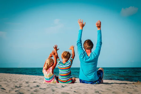 Far med liten sønn og datter som har det gøy på stranden – stockfoto