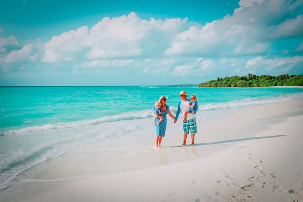 Familia feliz con dos niños a pie en la playa tropical —  Fotos de Stock