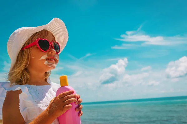 Sonnenschutz - glückliches kleines Mädchen mit Sonnencreme am Strand — Stockfoto