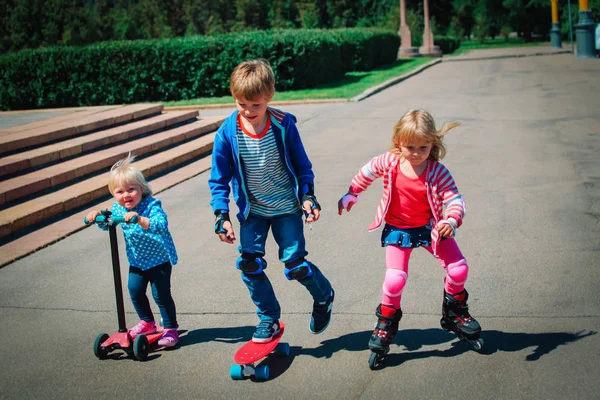 Fröhliche aktive Kinder fahren auf Roller, Scateboard und Rollschuhen — Stockfoto