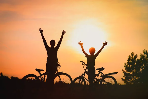 Silhouet van gelukkig moeder en zoon fietsen bij zonsondergang — Stockfoto
