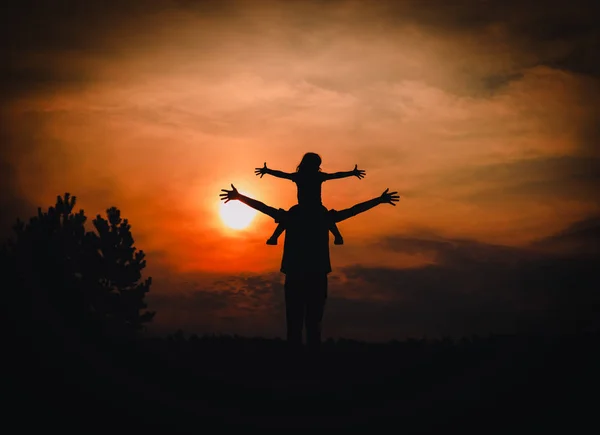 Father and little daughter silhouettes play at sunset sky — Stock Photo, Image