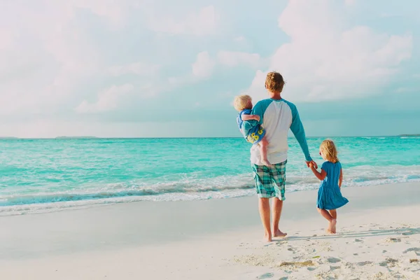 Vater und zwei kleine Töchter spazieren am Strand — Stockfoto