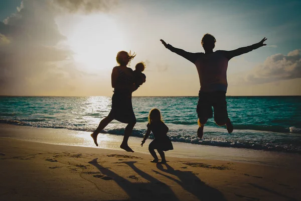 Família feliz com crianças em desfrutar de férias, jogar na praia do pôr do sol — Fotografia de Stock