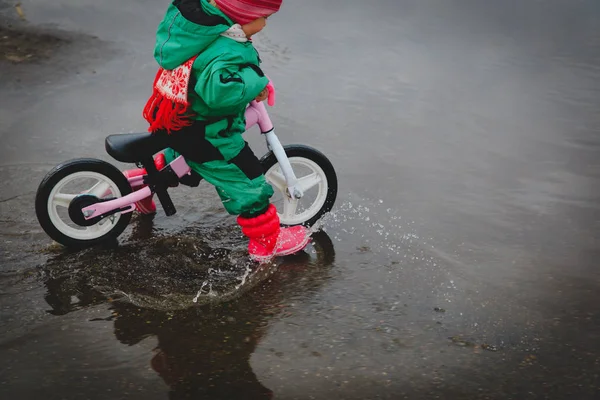 Bambina in bicicletta in pozzanghera d'acqua primaverile — Foto Stock