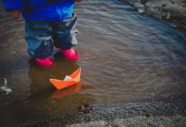 Gadis kecil bermain dengan perahu kertas di genangan air — Stok Foto