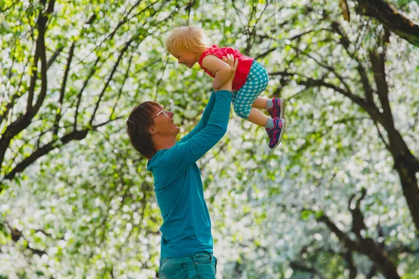 Lycklig far och lilla dotter spela i vår natur, äppelblom — Stockfoto