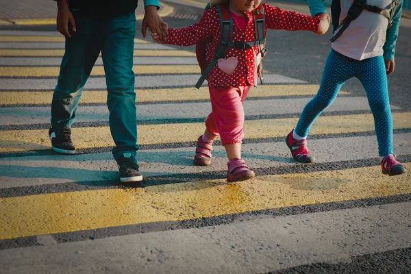 Jongen en meisjes hand in hand gaan naar school kruising de weg — Stockfoto