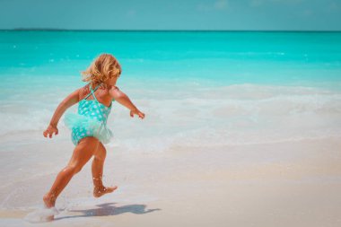 küçük kız oyun ile dalgalar kumsalda koşmak.