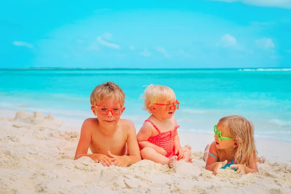 Süße kleine Jungen und Mädchen spielen mit Sand am Strand — Stockfoto